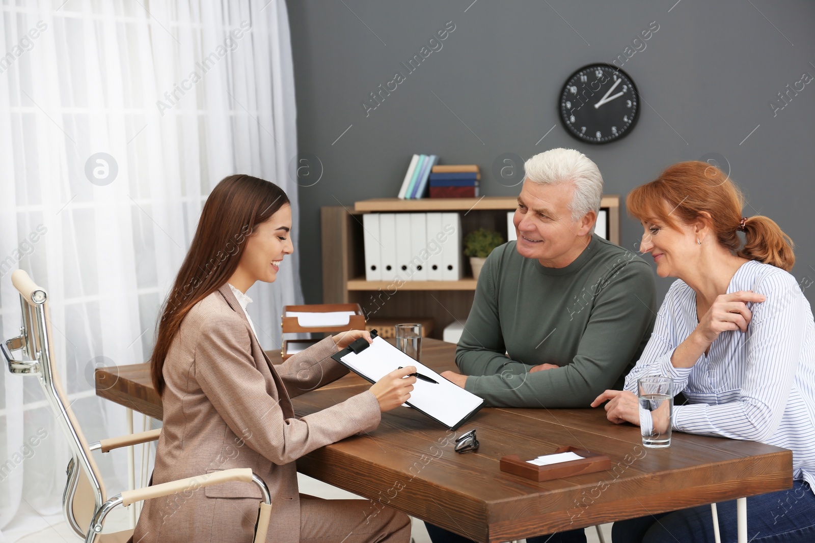 Photo of Young lawyer consulting senior couple in office