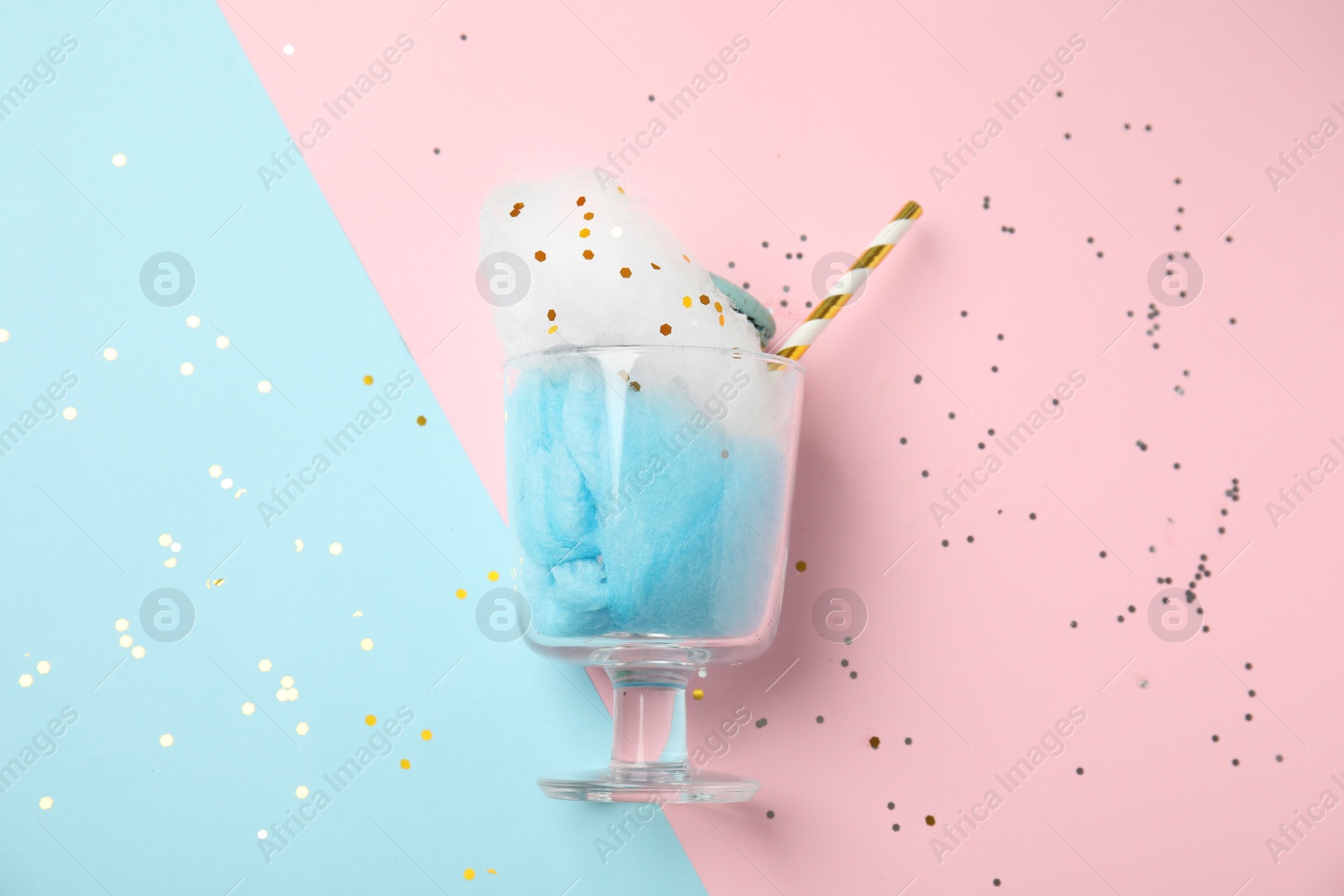 Photo of Glass with cotton candy and macaroon on color background, top view