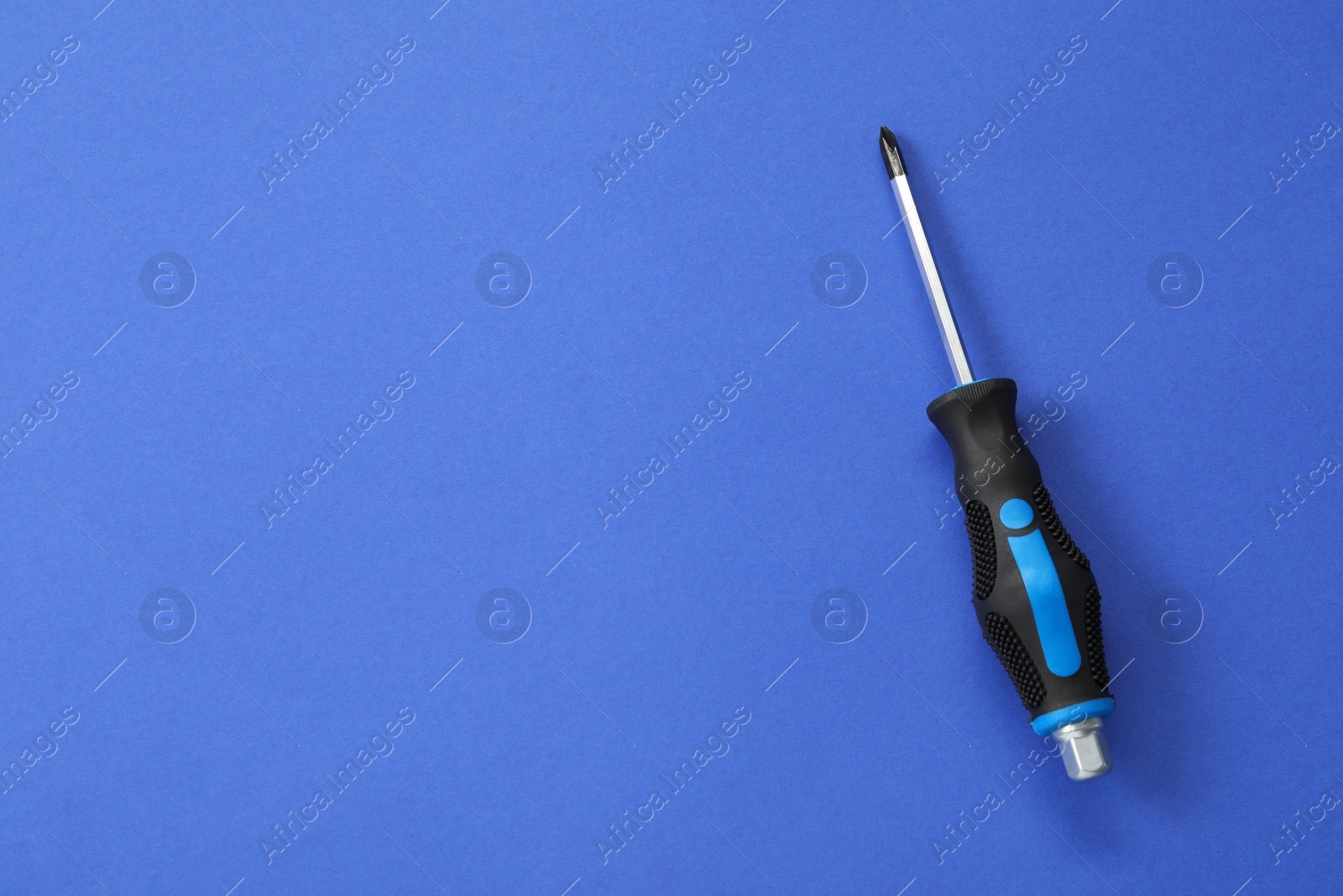 Photo of Screwdriver with black handle on blue background, top view. Space for text