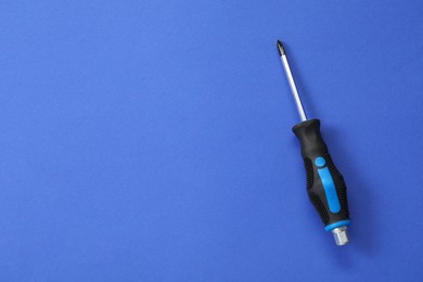 Photo of Screwdriver with black handle on blue background, top view. Space for text