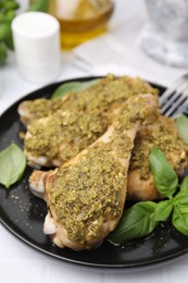 Photo of Delicious fried chicken drumsticks with pesto sauce and basil on white table, closeup