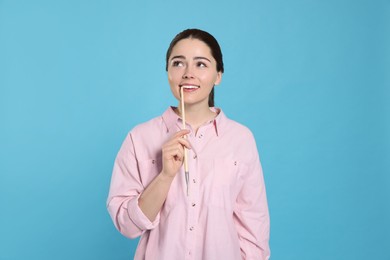 Photo of Woman with paintbrush on light blue background. Young artist