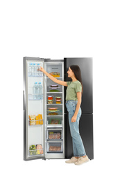 Young woman taking bottle of water from refrigerator on white background