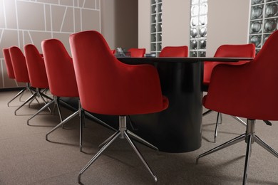 Photo of Stylish red office chairs and large table in empty conference room