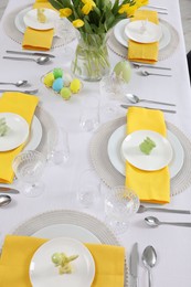 Festive table setting with glasses, painted eggs and vase of tulips, view from above. Easter celebration