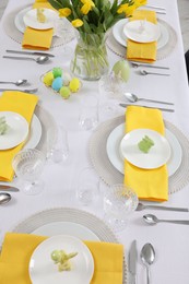 Photo of Festive table setting with glasses, painted eggs and vase of tulips, view from above. Easter celebration