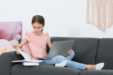 Photo of Girl with laptop and books on sofa at home
