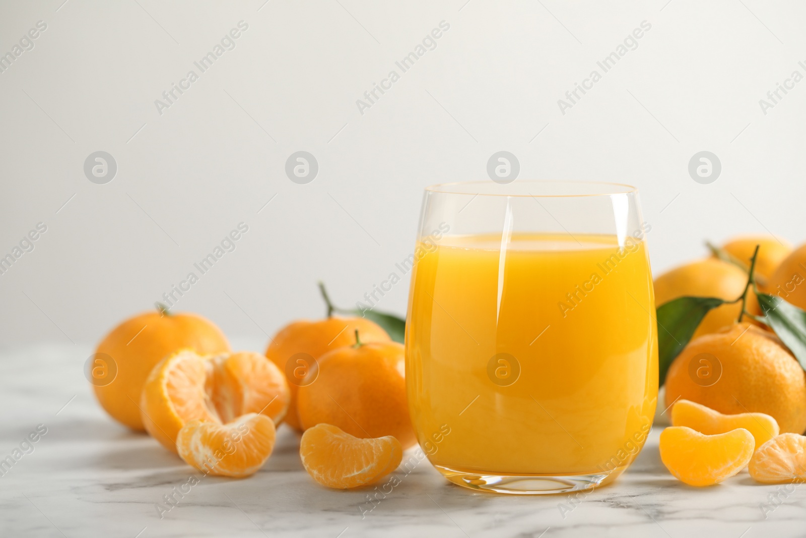 Photo of Glass of fresh tangerine juice and fruits on marble table