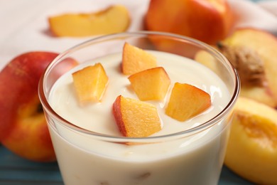 Photo of Tasty peach yogurt with pieces of fruit in glass on table, closeup