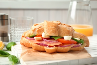 Photo of Tasty croissant sandwich with salmon on table