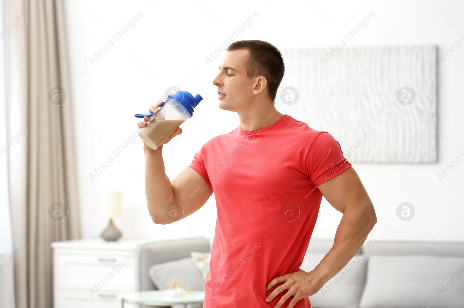 Photo of Athletic young man drinking protein shake at home