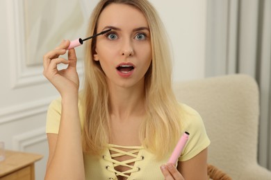 Photo of Beautiful emotional woman applying mascara at home