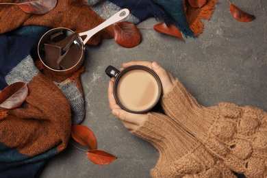 Photo of Woman in autumn sweater holding hot cozy drink at table, top view