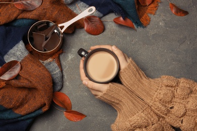 Woman in autumn sweater holding hot cozy drink at table, top view