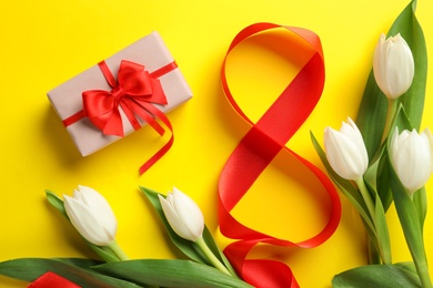 Photo of 8 March card design with tulips and gift on yellow background, flat lay. International Women's Day