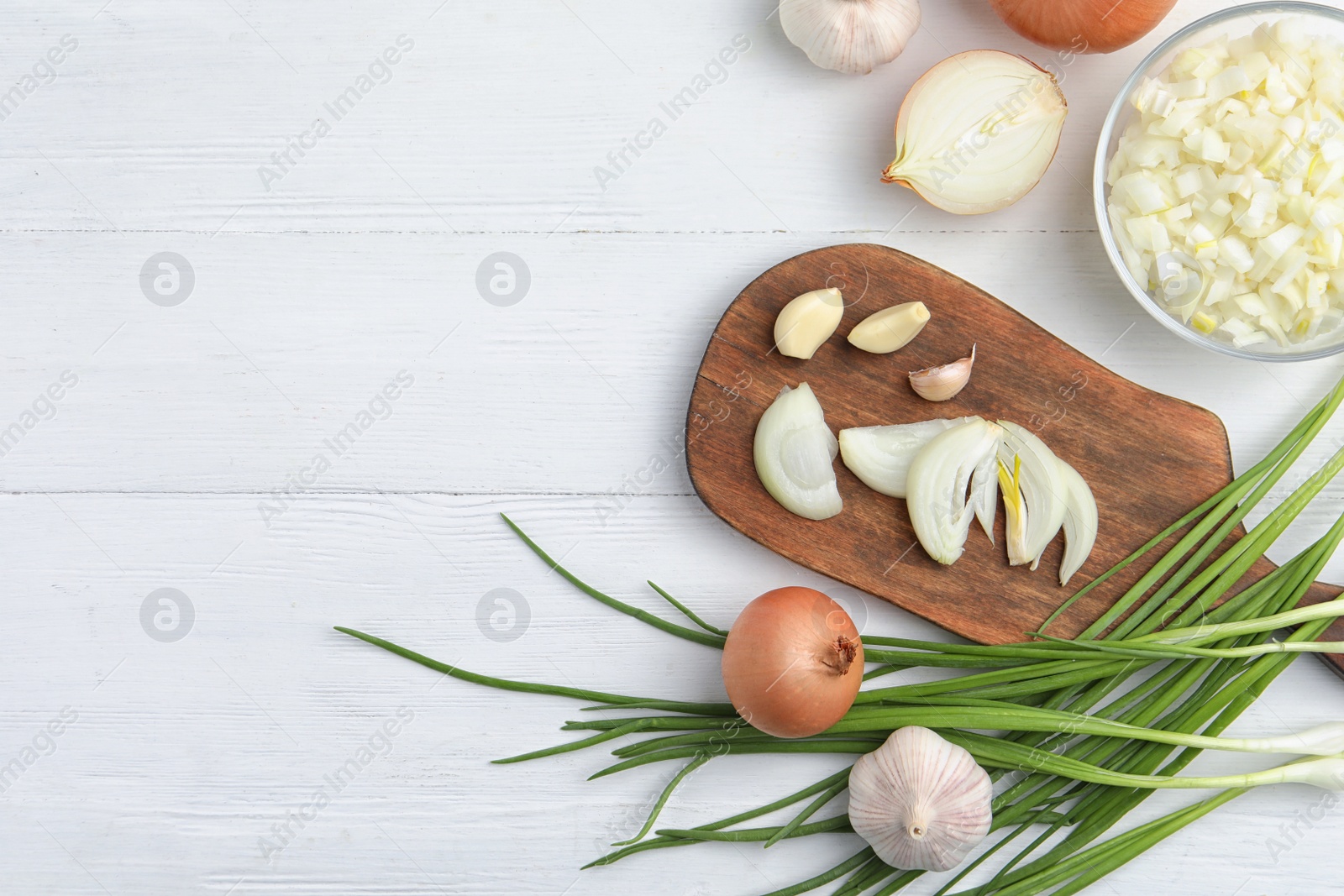 Photo of Flat lay composition with cut onion and garlic on white wooden table. Space for text