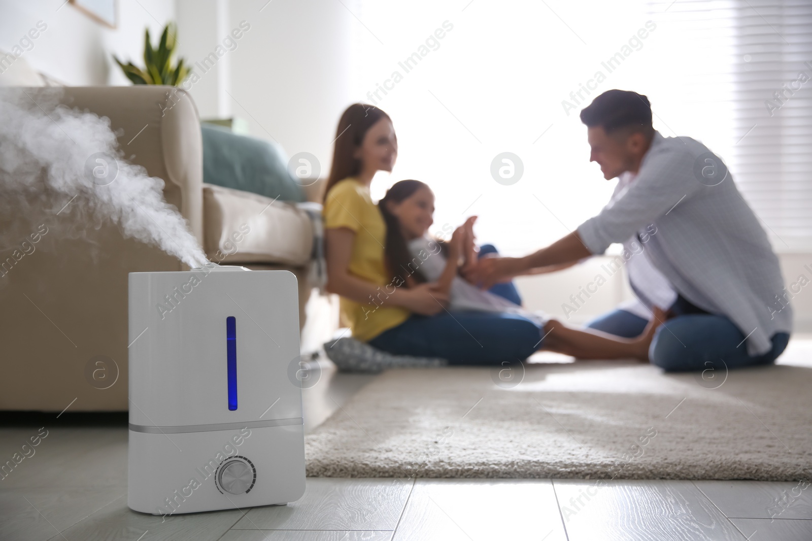 Photo of Modern air humidifier and blurred family on background