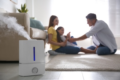 Modern air humidifier and blurred family on background