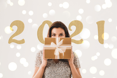 Beautiful woman with Christmas gift against blurred background