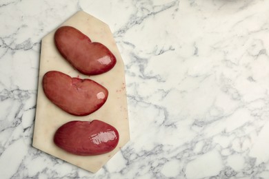 Fresh raw pork kidneys on white marble table, top view. Space for text