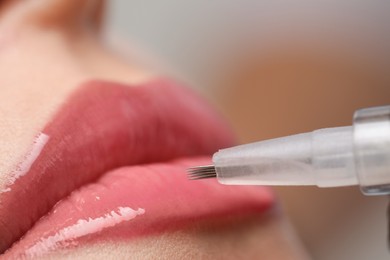 Young woman during procedure of permanent lip makeup in beauty salon, closeup