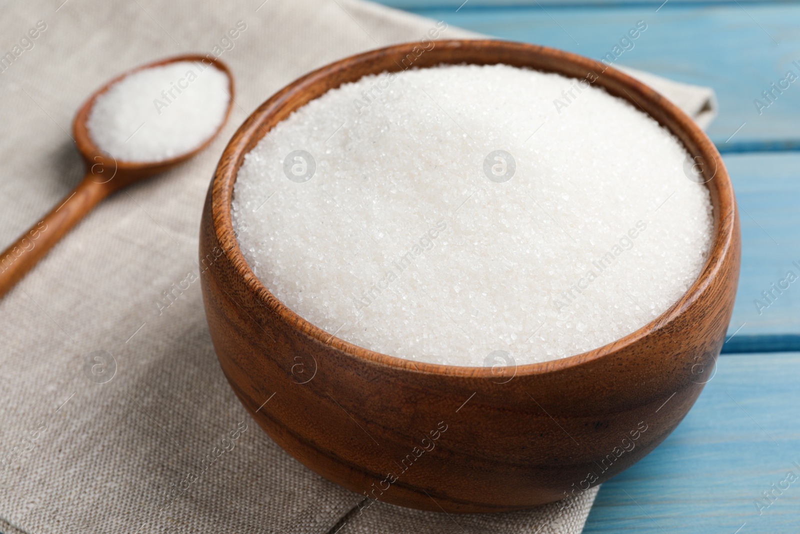 Photo of Granulated sugar on turquoise wooden table, closeup