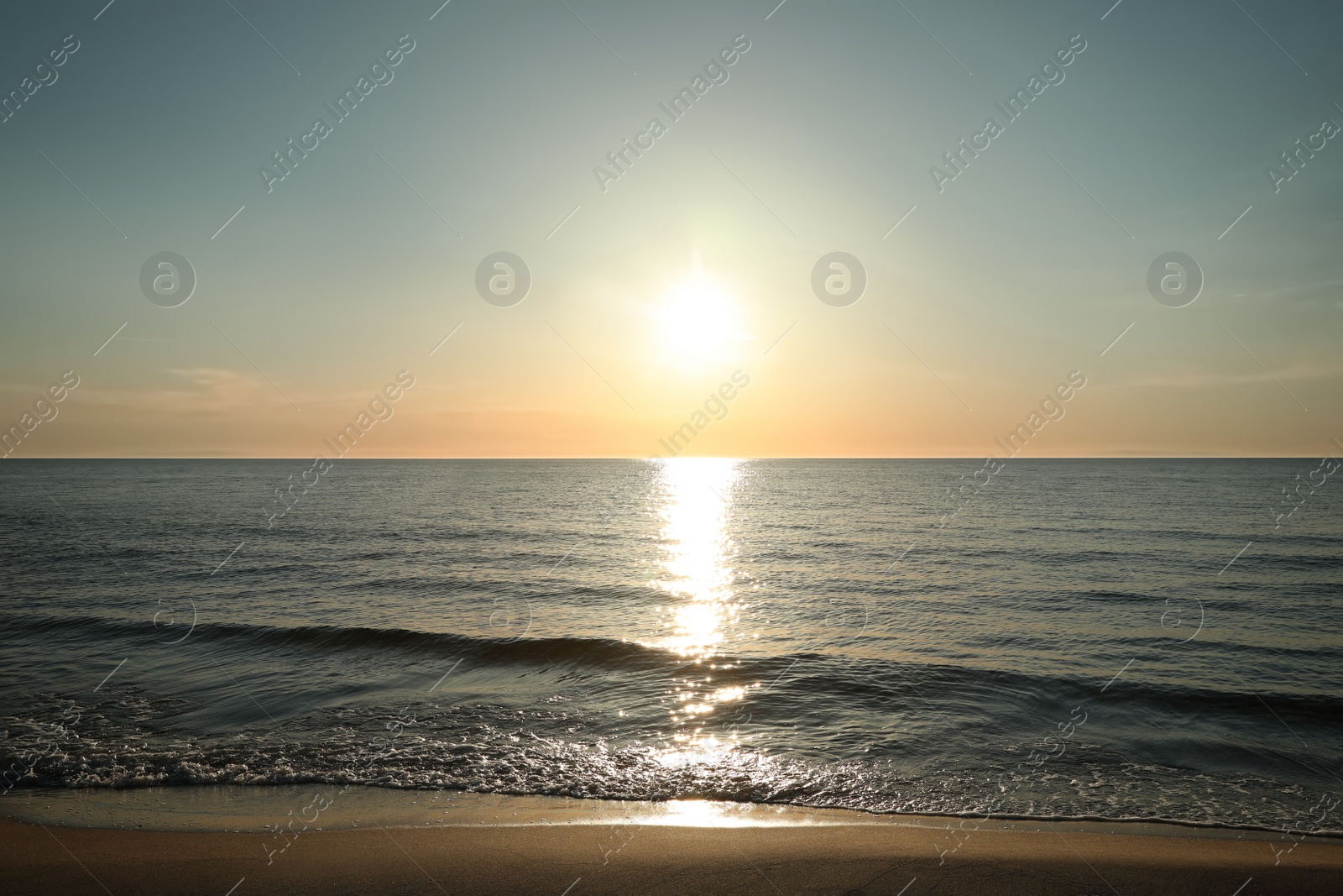 Photo of Picturesque view of sandy beach and sea at sunset