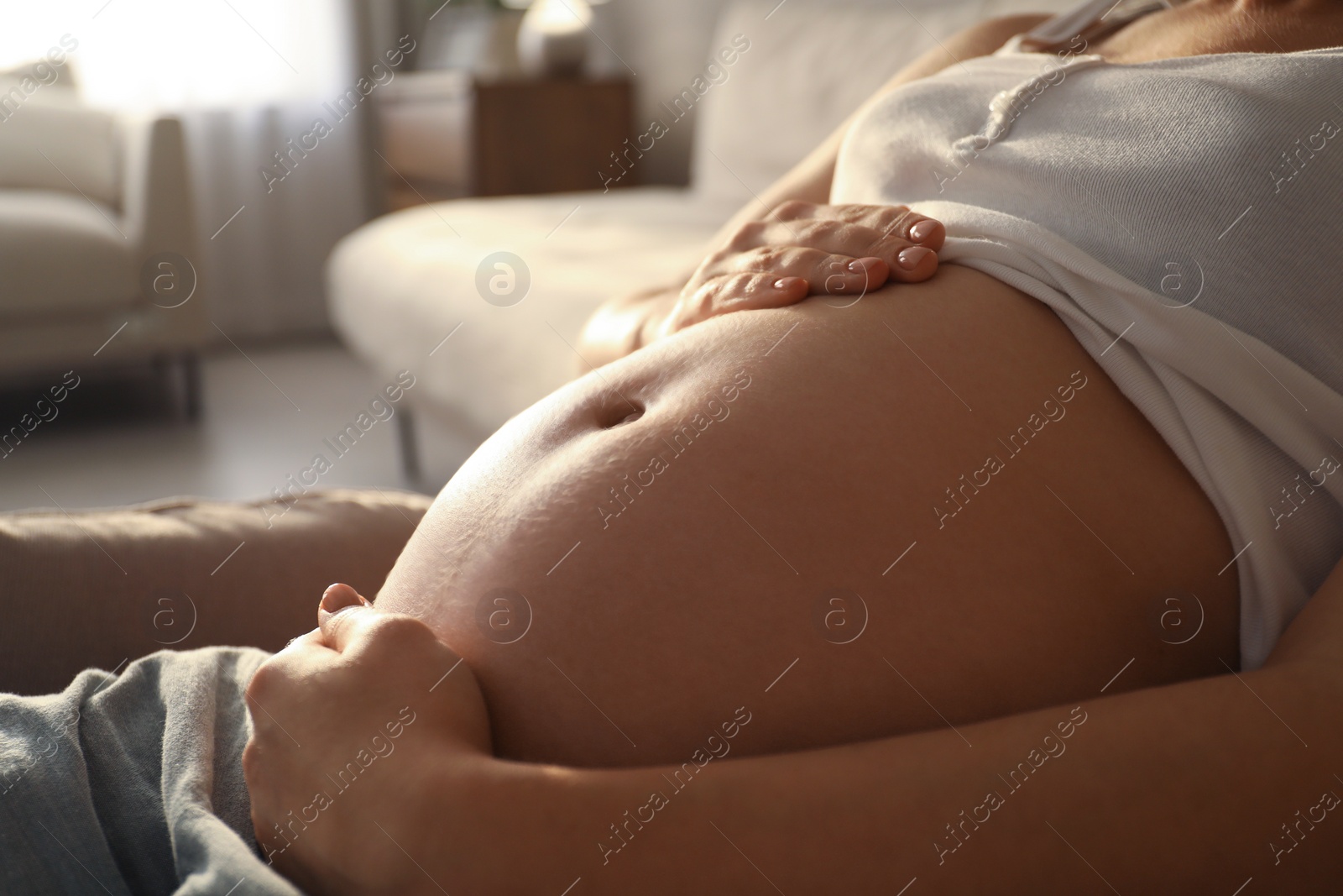 Photo of Pregnant young woman touching belly at home, closeup