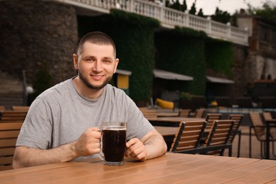Photo of Man with glass of dark beer in outdoor cafe, space for text
