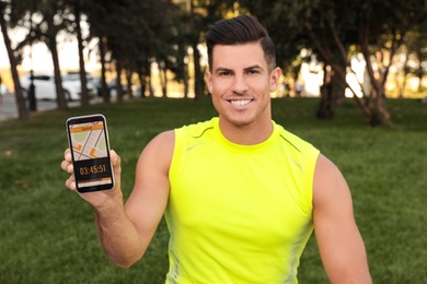 Photo of Man showing smartphone with fitness app in park