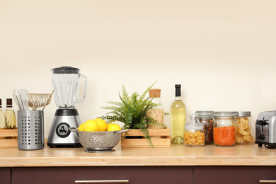 Wooden countertop with appliances and products near white wall. Kitchen interior idea