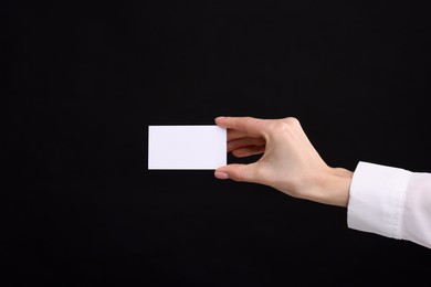 Woman holding blank business card on black background, closeup. Space for text