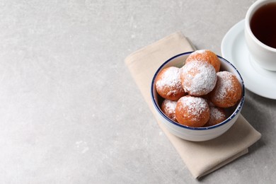 Delicious sweet buns in bowl and cup of tea on gray table, space for text