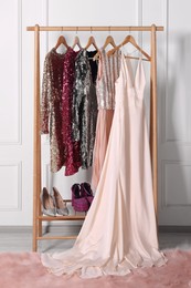 Photo of Rack with collection of stylish dresses and shoes in room. Preparing for party