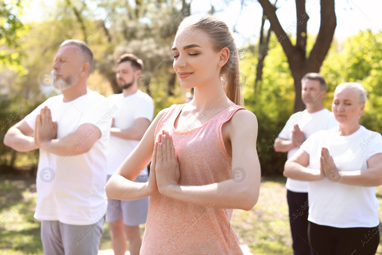 Photo of Group of people practicing yoga in park on sunny day