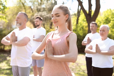 Group of people practicing yoga in park on sunny day