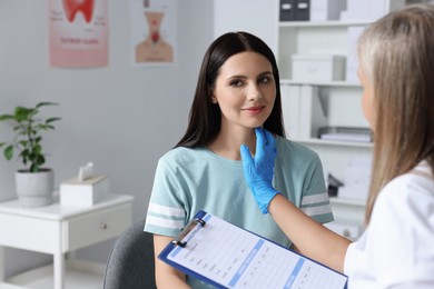 Endocrinologist with clipboard examining thyroid gland of patient at hospital