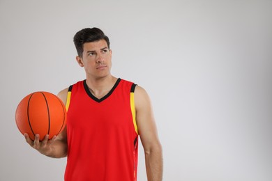 Basketball player with ball on grey background. Space for text