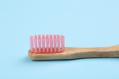 Photo of Toothbrush made of bamboo on light blue background, closeup