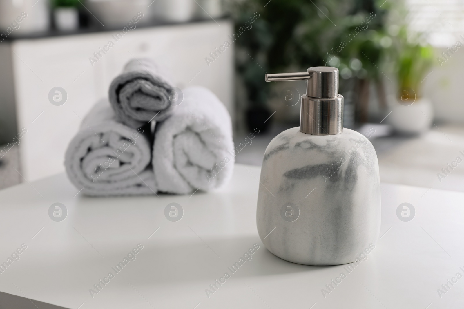 Photo of Dispenser with liquid soap near towels on white table in bathroom, space for text