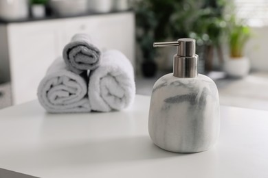 Photo of Dispenser with liquid soap near towels on white table in bathroom, space for text