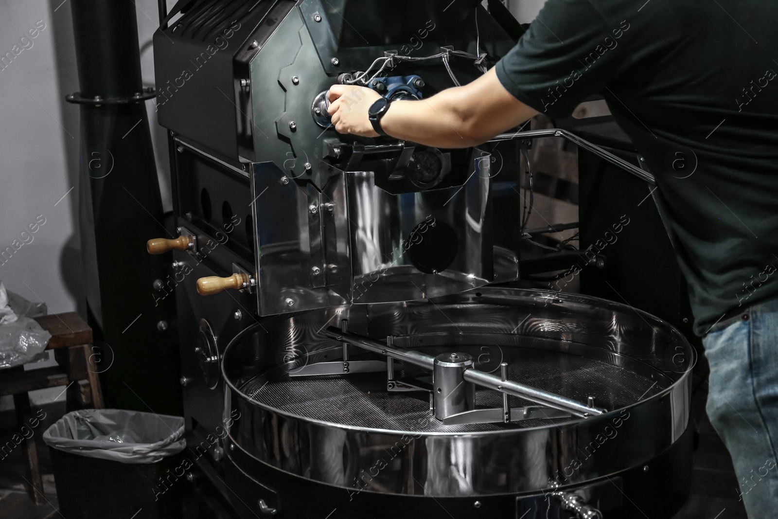 Photo of Man near coffee roaster machine indoors, closeup