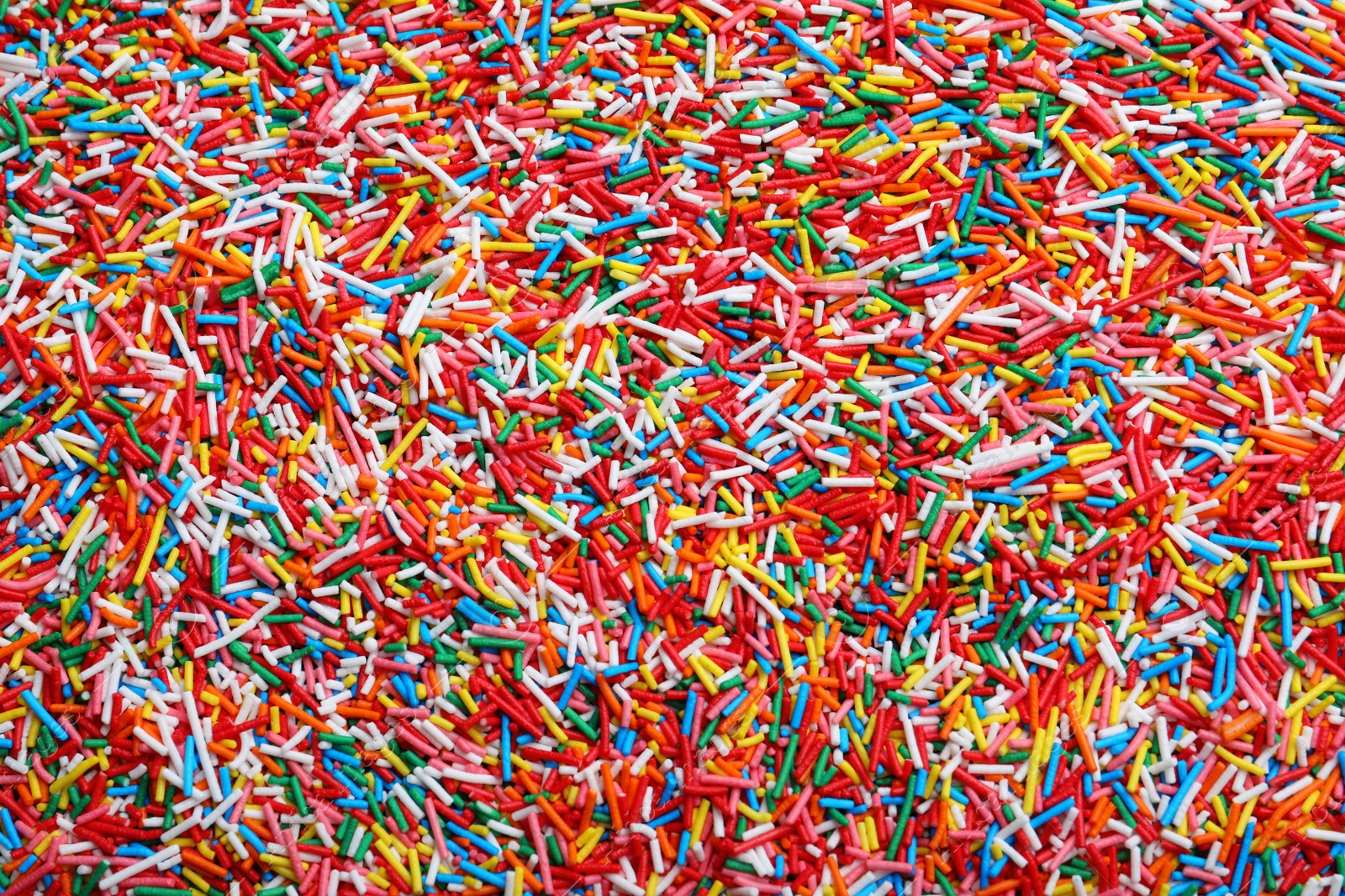 Photo of Bright colorful sprinkles as background, top view. Confectionery decor