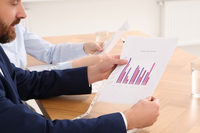 Businesspeople working with charts at wooden table in office, closeup
