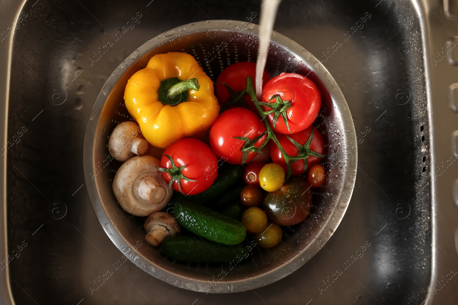 Photo of Washing different vegetables with tap water in metal colander inside sink, top view