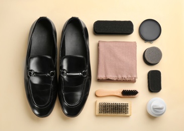 Photo of Flat lay composition with shoe care accessories and footwear on beige background