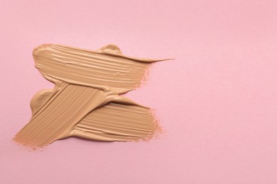 Photo of Sample of liquid skin foundation on pink background, top view. Space for text