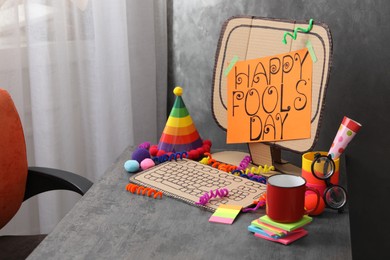 Photo of Fake computer with words Happy Fool's Day on table in office