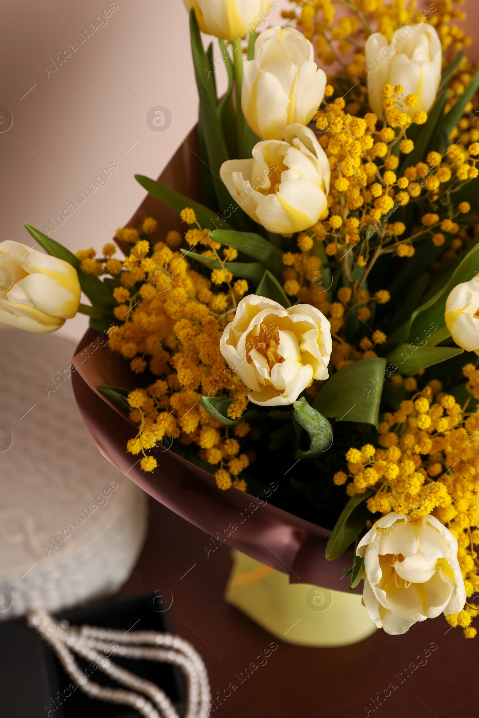 Photo of Bouquet with beautiful spring flowers and necklace on wooden table, above view