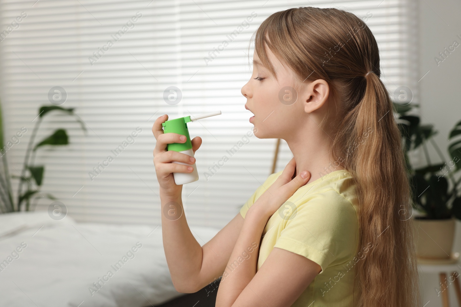 Photo of Little girl using throat spray at home. Space for text